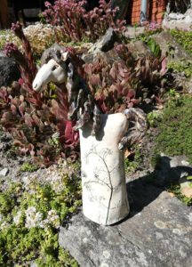 Keramický koník s květinovým motivem ve skalce
